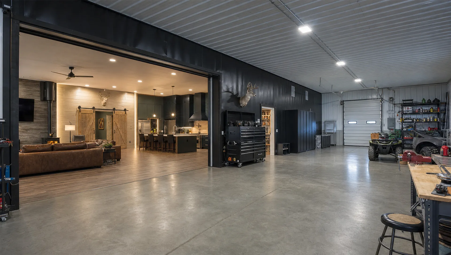 A finished barndominium interior connected to a large workshop bay, showing durable flooring, bright overhead lighting, wall accents, metal wall panels, storage cabinets and wide equipment doors, viewed from the workshop side looking toward the living space.